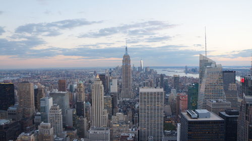 Aerial view of buildings in city against cloudy sky