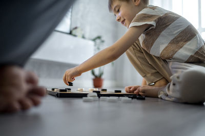 Happy son playing checkers with father at home