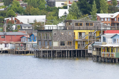 Houses by river against buildings in city