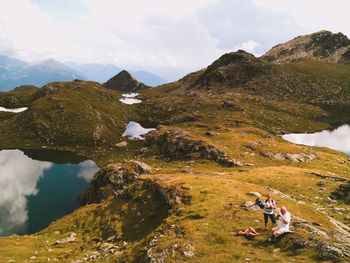 Group of people having a break from hiking. scenic view of mountains / lake against sky