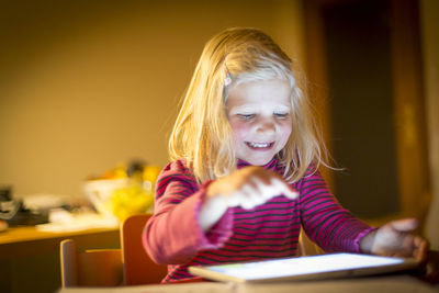 Girl using digital tablet on table at home