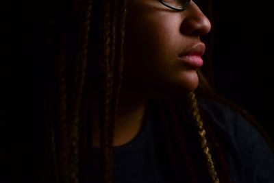 Midsection of young woman looking away against black background