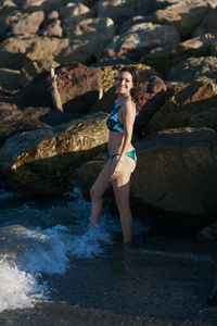 Full length of woman standing on rock at shore