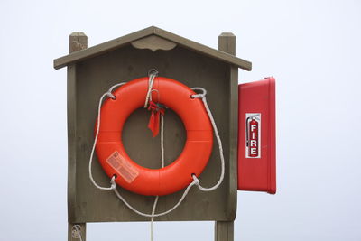 Close-up of life preserver information sign on pole against clear sky