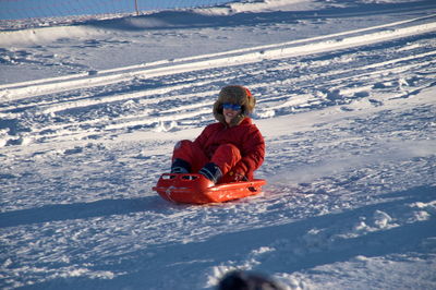 Boy sliding downhill on sledge on snow