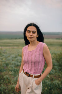 Portrait of smiling young woman standing on field