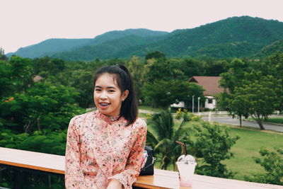 Portrait of smiling young woman against plants