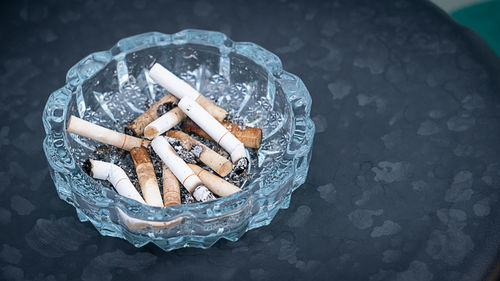 High angle view of cigarette butts in ashtray on table