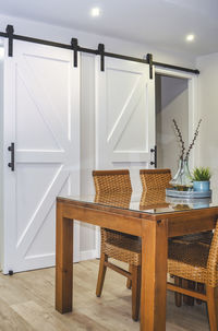 Bright dining room with a wooden table and rattan chairs. sliding barn doors in the background.