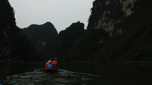 People on boat in river against sky