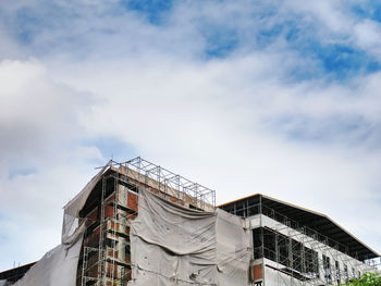 Large under construction building with frames and covers against cloudy blue sky