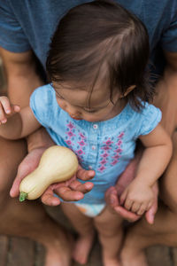 Midsection of father giving squash to daughter at home