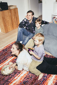 High angle view of kids playing video game while sitting with parents at home