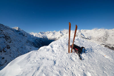 Person skiing on snowcapped mountain against blue sky