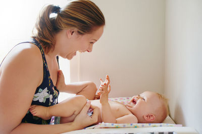 Smiling mother playing with baby at home