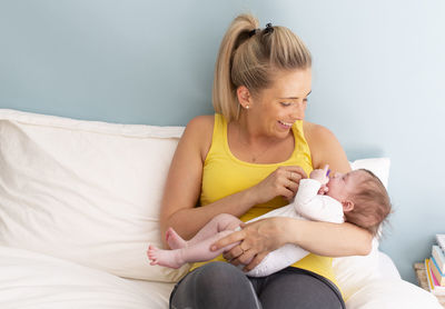 Young woman sitting on bed at home