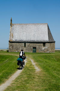 Rear view of mature man riding bicycle towards chapel