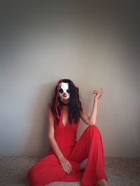 Woman dressed in red wearing scary clown mask