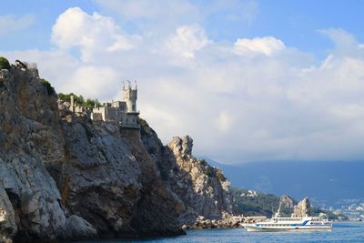 Swallows nest on cliff by sea against sky