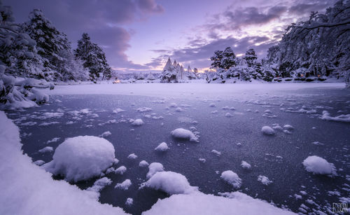 Snow on lake against sky during sunset