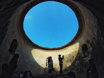 Low angle view of people standing against blue sky