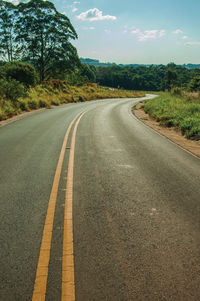 Countryside paved road on hilly landscape covere by trees in a sunny day near pardinho, brazil.