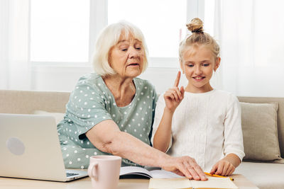 Young woman using laptop while sitting on sofa at home