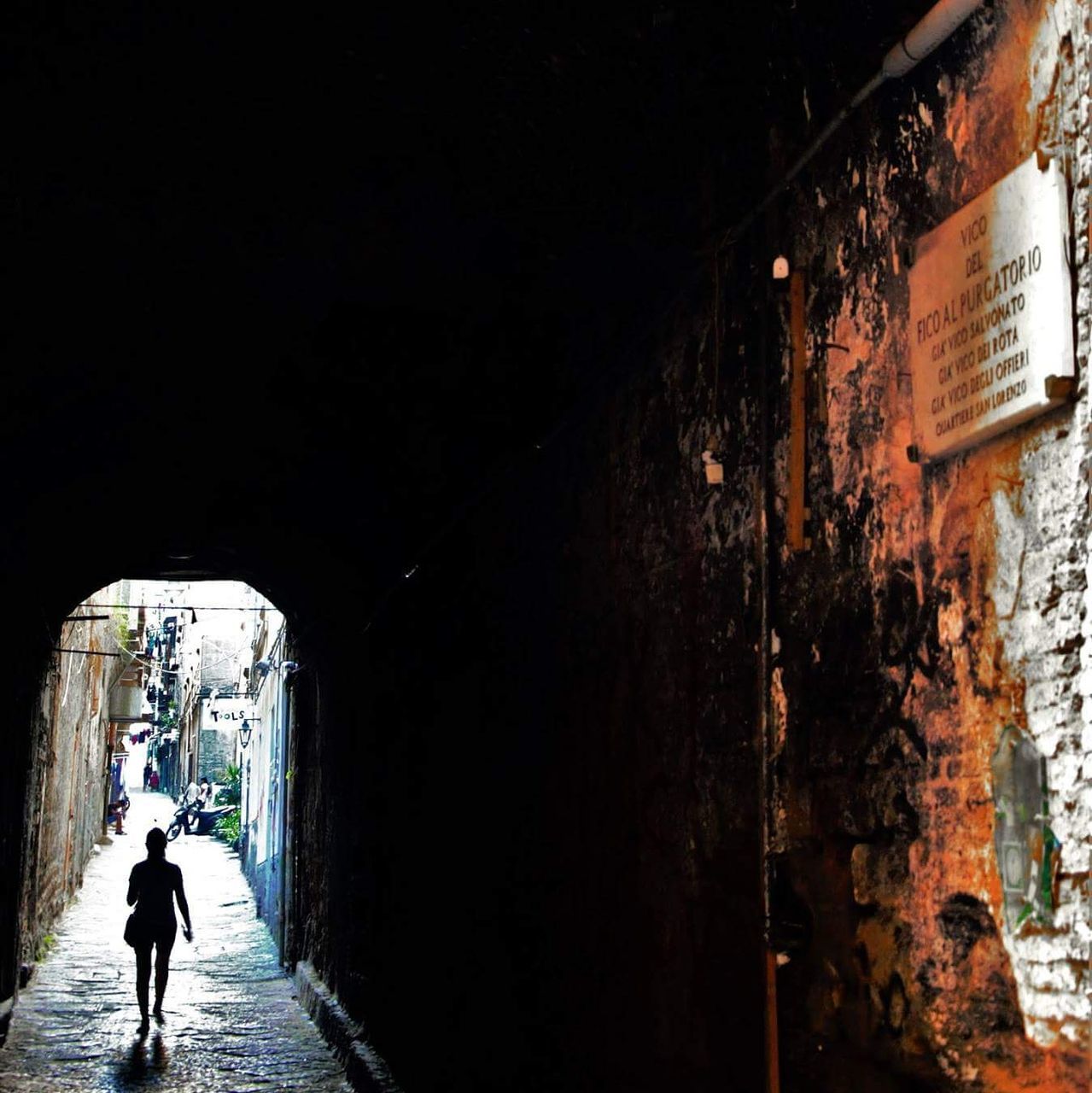 REAR VIEW OF MAN WALKING ON ALLEY