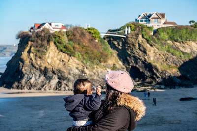 Mother carrying son while standing on land