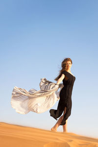 Young woman with umbrella against clear sky