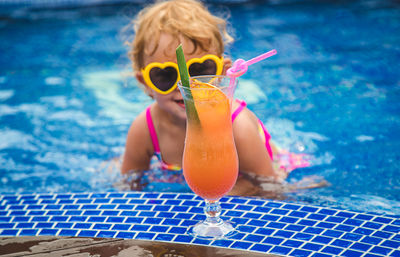 Young woman wearing sunglasses while swimming in pool