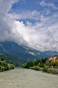 Scenic view of river and mountains against cloudy sky