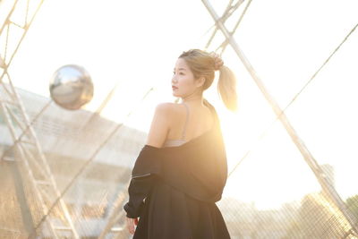 Full length of young woman standing against wall