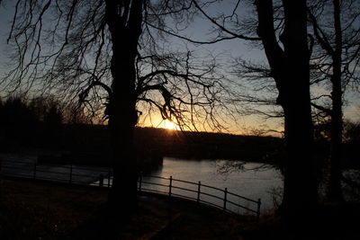 Silhouette of bare trees against sky at sunset