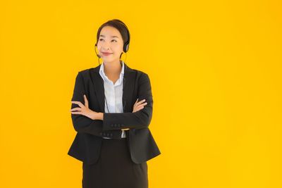 Portrait of a smiling young woman against yellow background