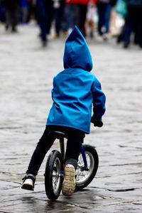Rear view of child cycling on footpath