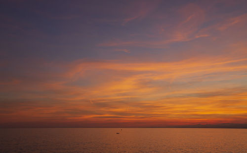 Scenic view of sea against dramatic sky during sunset