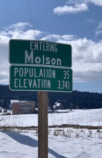 Information sign on snow covered field against sky