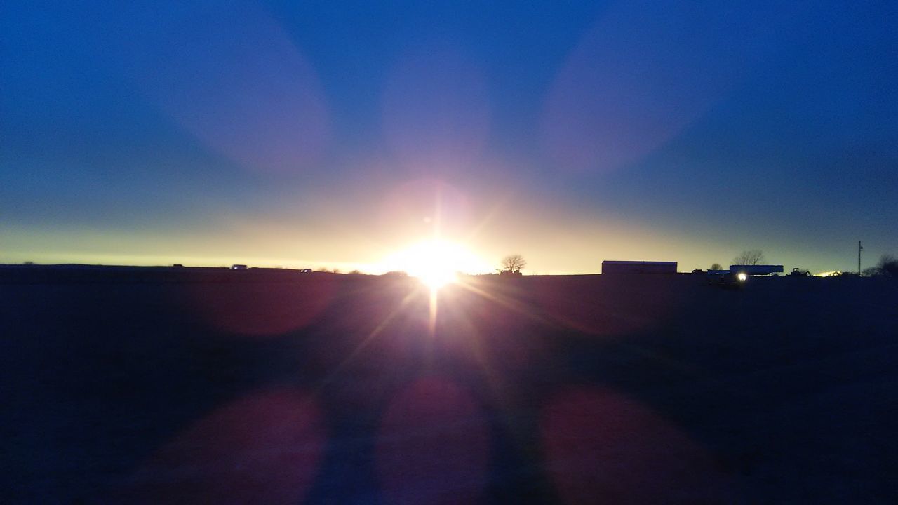 SUN SHINING OVER SILHOUETTE LANDSCAPE