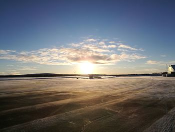Airplane on runway against sky during sunset