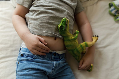 Midsection of boy with toy sleeping on bed at home