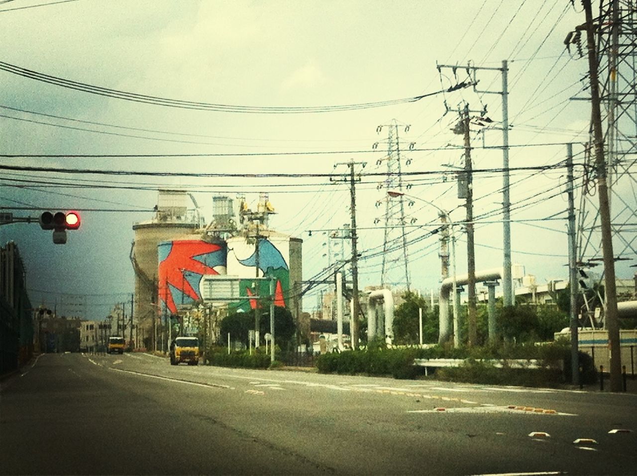 road, power line, street, transportation, building exterior, electricity pylon, architecture, built structure, the way forward, road marking, cable, power supply, sky, electricity, road sign, city, communication, guidance, day, outdoors