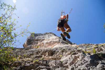 Low angle view of man jumping on rock