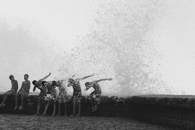 People swimming in pool against sea