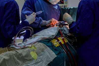 Midsection of doctors operating patient in hospital