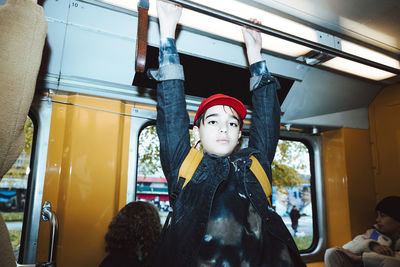 Portrait of boy holding handle while traveling in tram on weekend