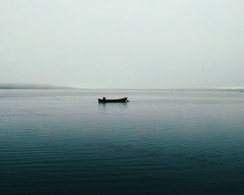 Boat anchored at lake against sky