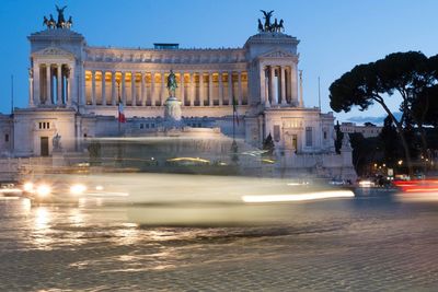 Light trails on road against historic buildings