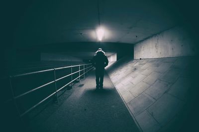 Rear view of man walking in illuminated corridor