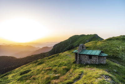 House on mountain against sky during sunset